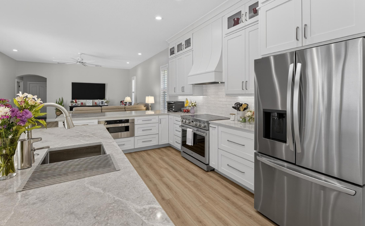 kitchen with deep sink, tile backsplash, wood look flooring, built-in appliances in Tampa, FL