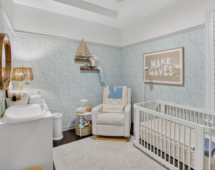 Baby nursery with light blue wallpaper, wood floors and an area rug in Westchase, FL