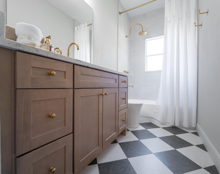 bathroom remodel with black and white tile floors, gold hardware and bath fixtures in Lutz, FL