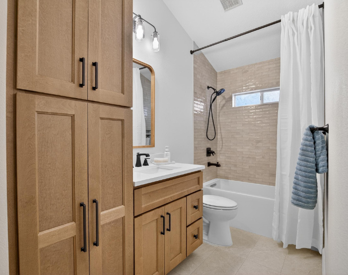 bath remodel with custom cabinets and matching vanity with black hardware and bath fixtures in Lutz